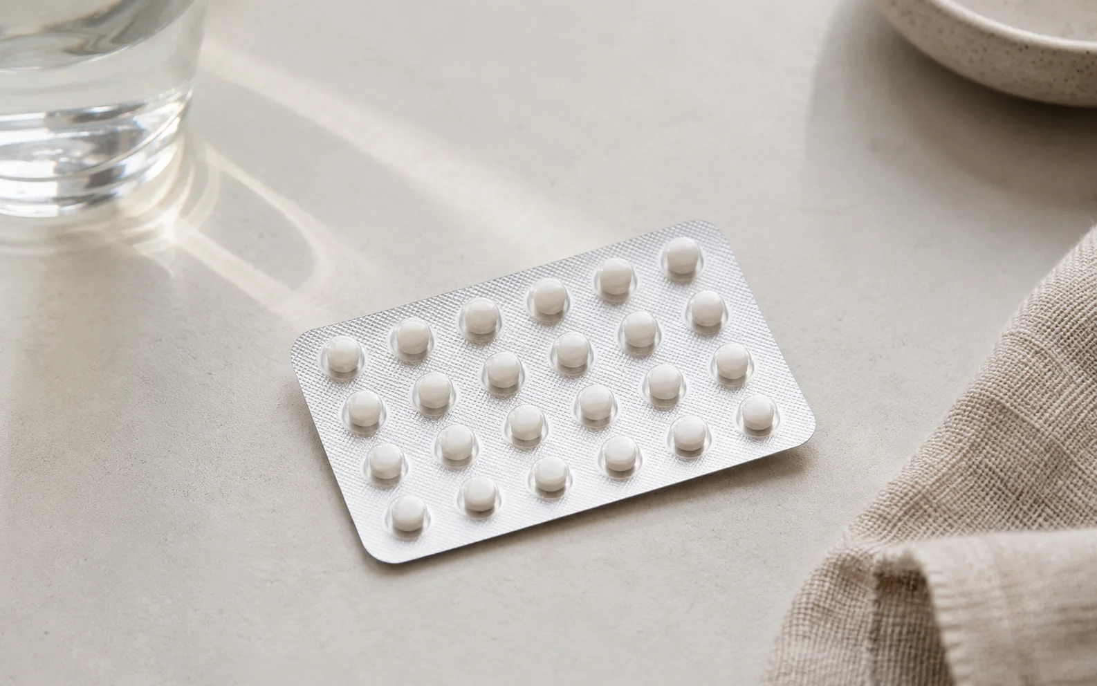 A plain blister pack of small unmarked tablets on a clean light surface