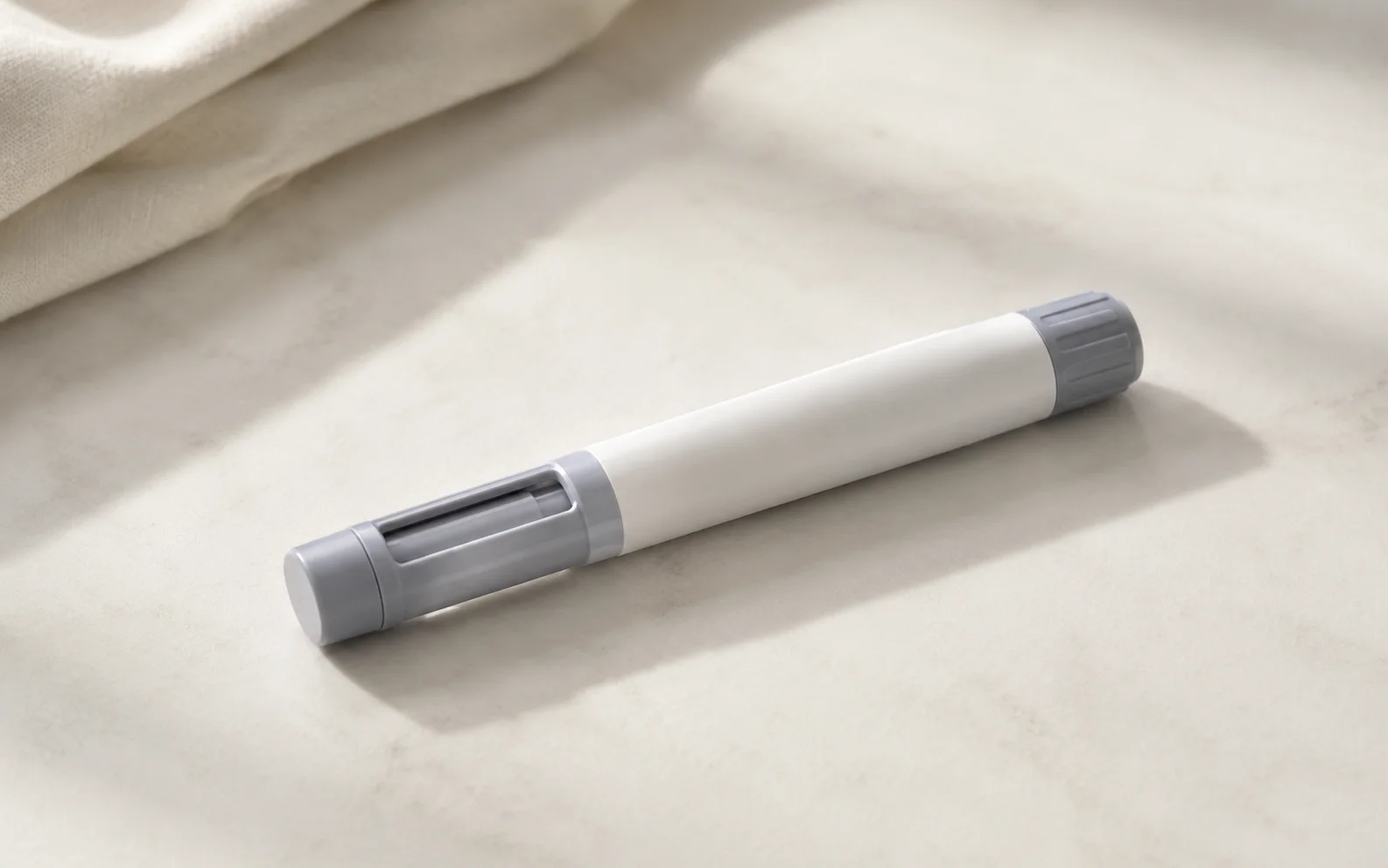 A plain unbranded medical injector pen resting on a calm neutral surface