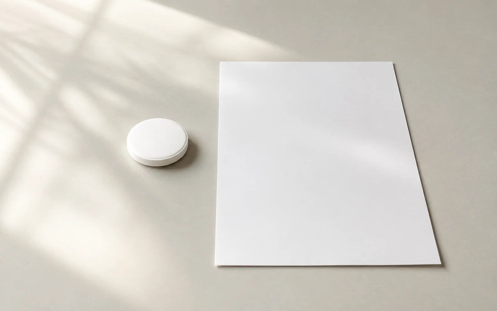 A plain unbranded tablet resting on a calm neutral surface beside a blank document