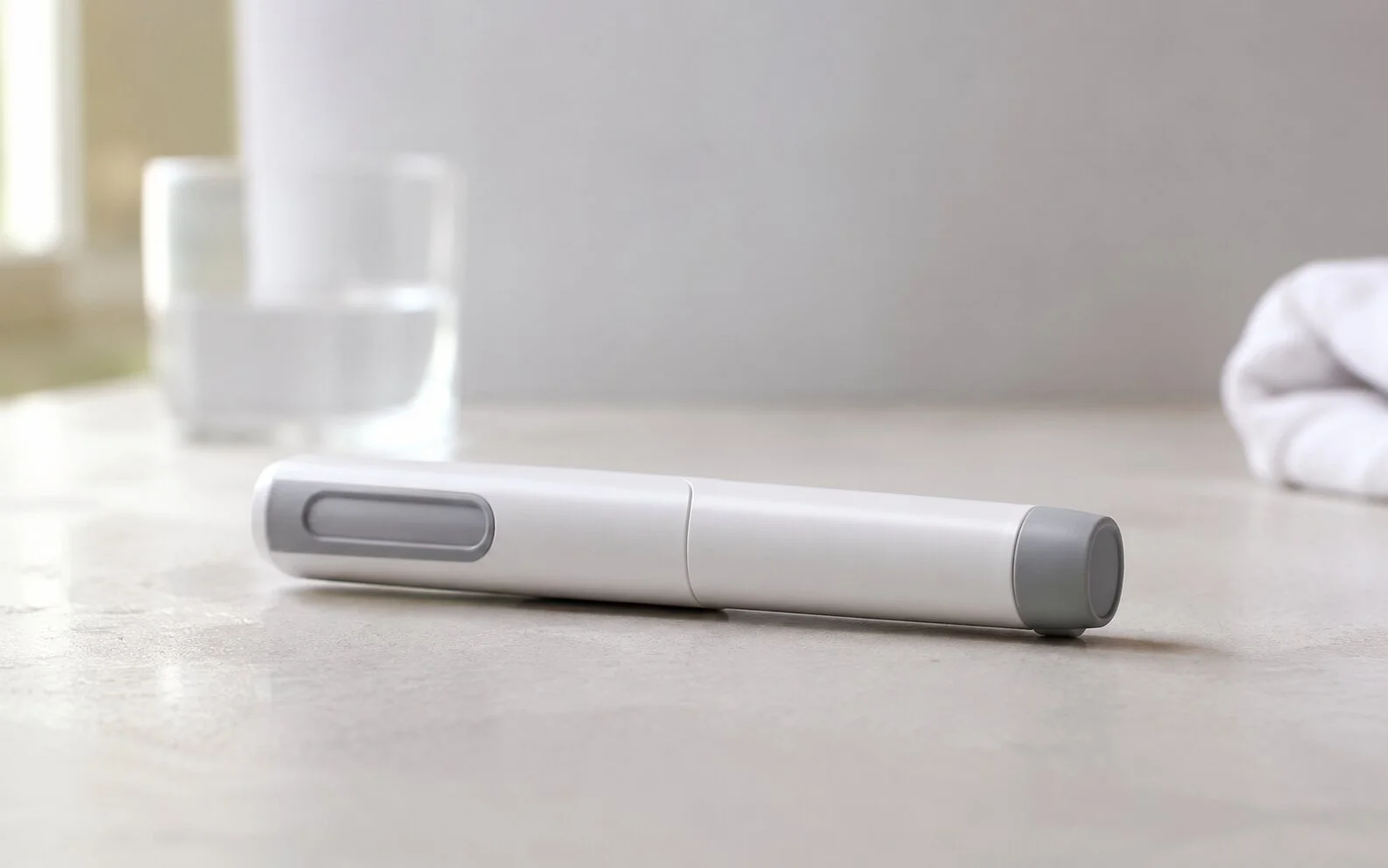A plain unbranded medical injector pen resting on a calm neutral surface