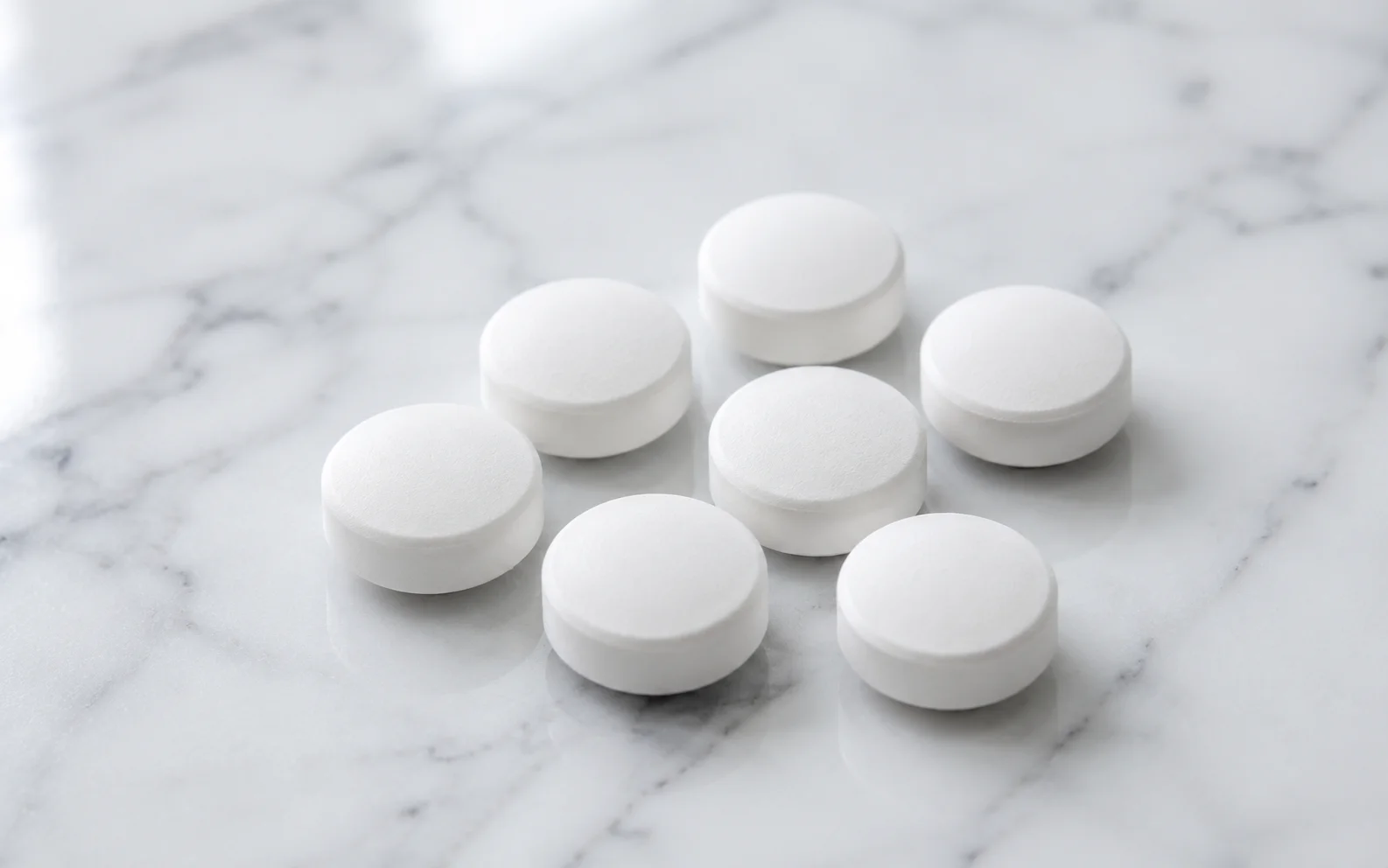 Plain unmarked white tablets arranged on a clean clinical surface