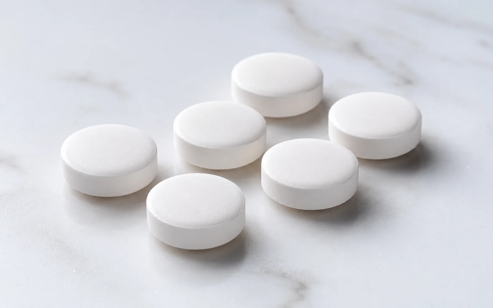 Plain unmarked white oral tablets arranged on a clean clinical surface