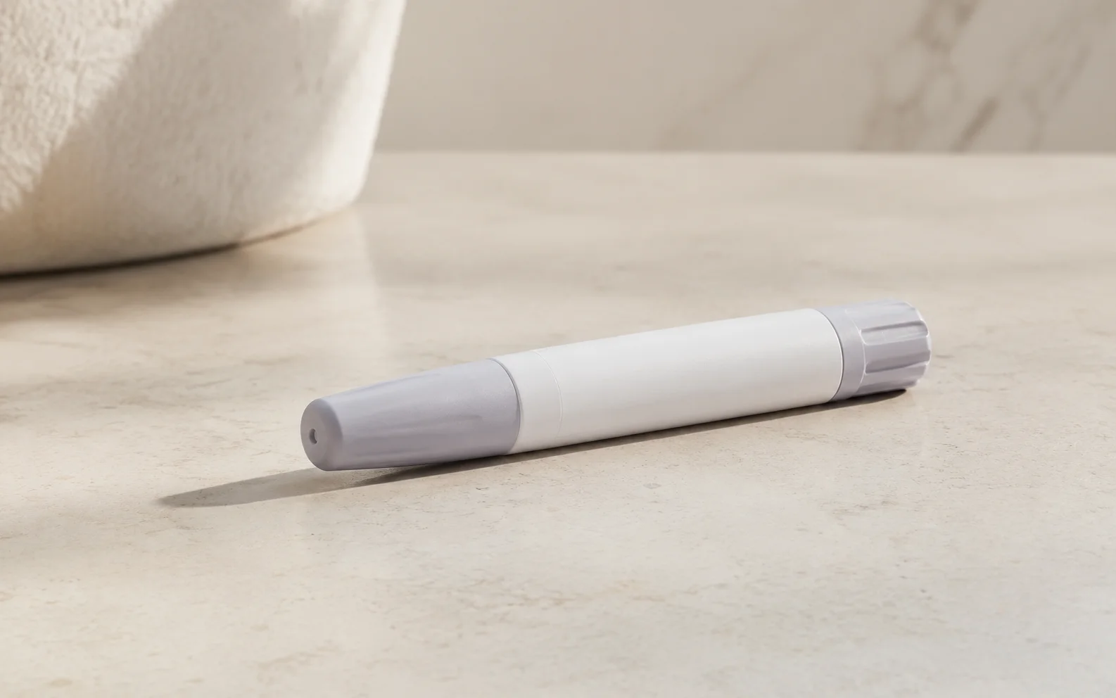 A plain unbranded medical injector pen on a clean neutral surface