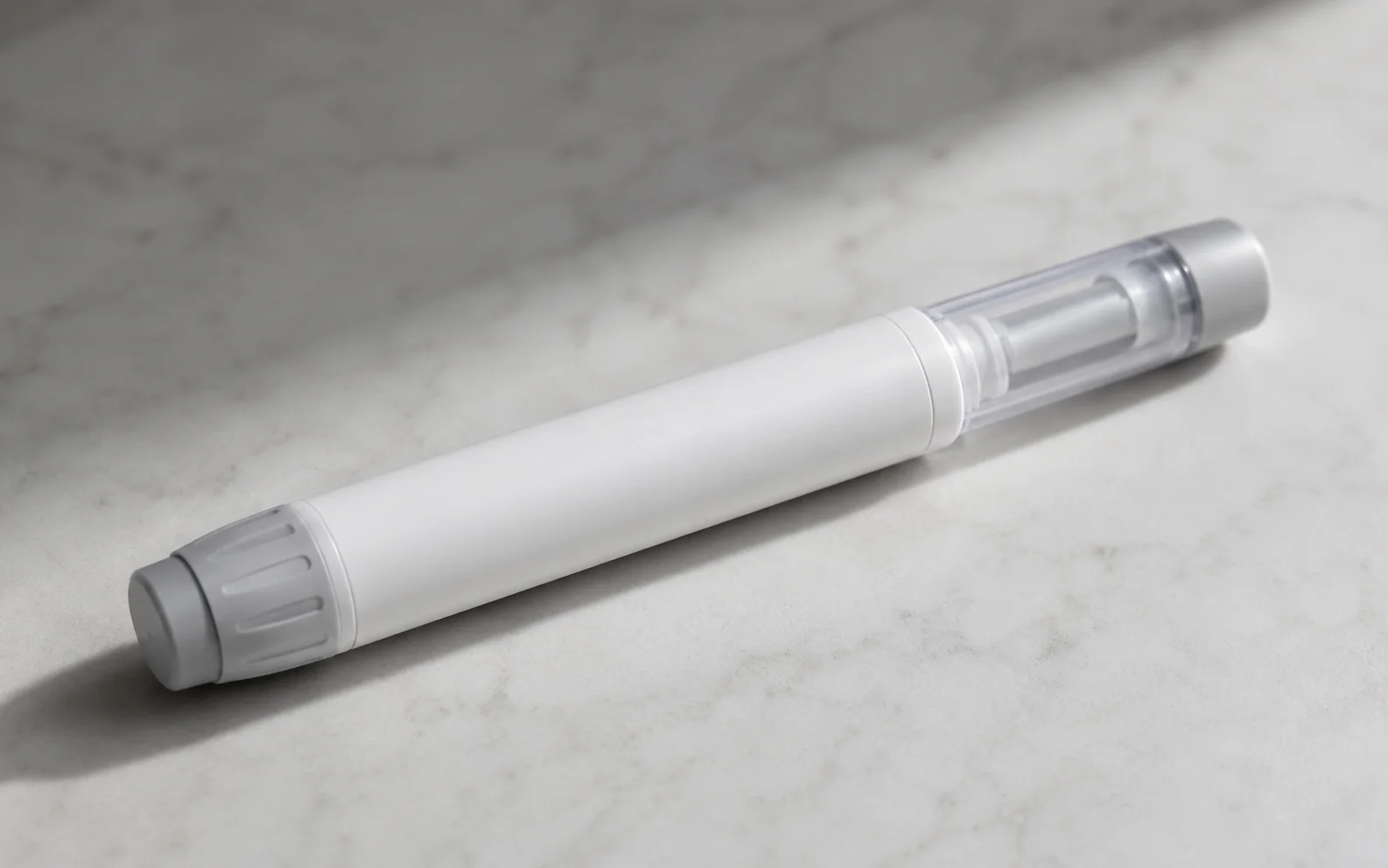 A plain unbranded medical injector pen resting on a clean neutral surface