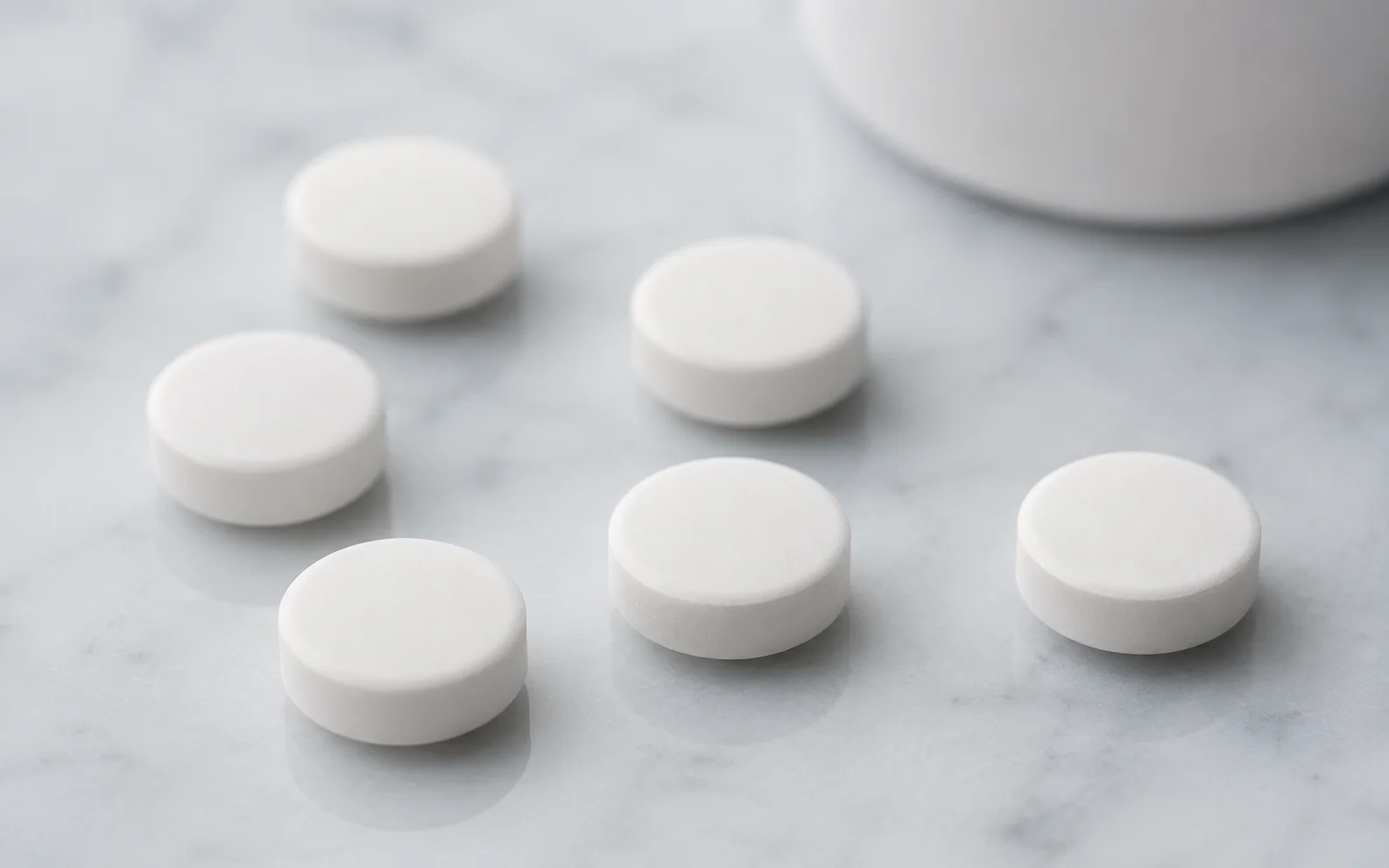Plain unmarked white oral tablets arranged on a clean clinical surface