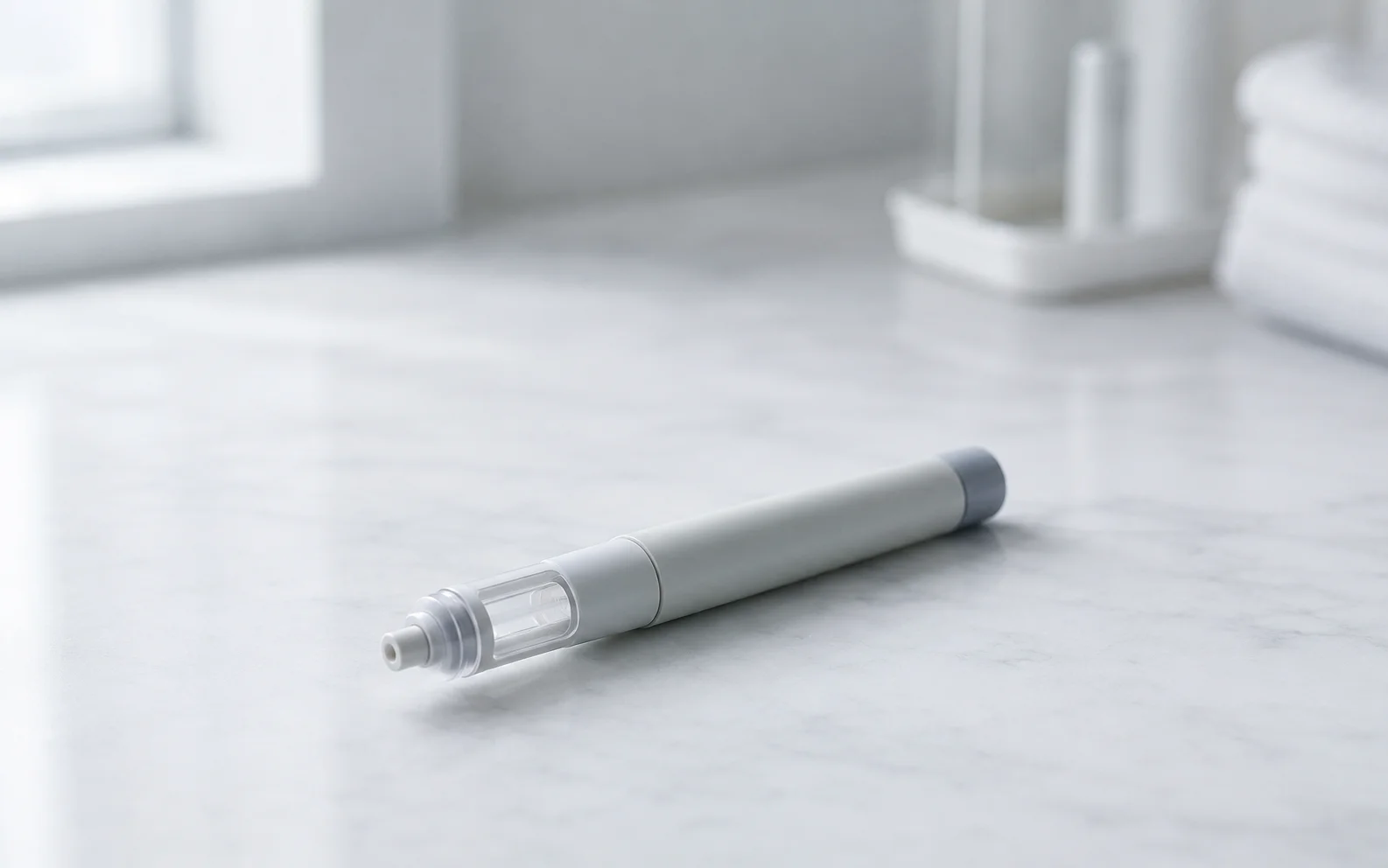 A plain unbranded medical injector pen resting on a clean clinical surface