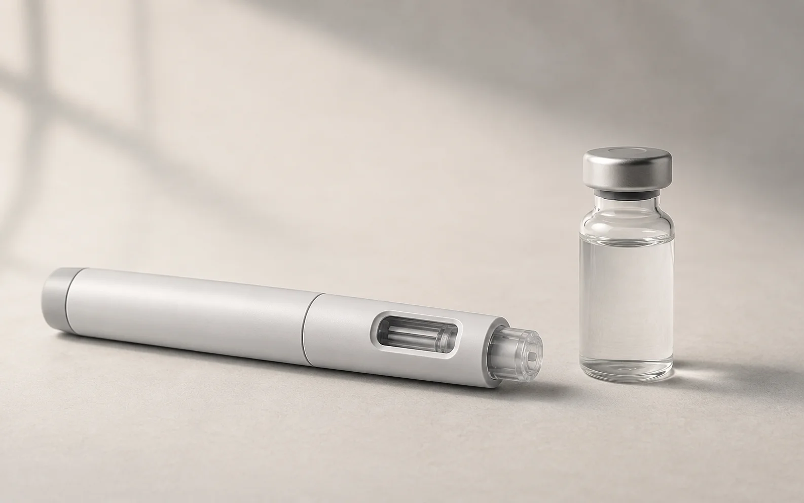 A plain unbranded medical injector pen and a plain vial on a clean neutral surface