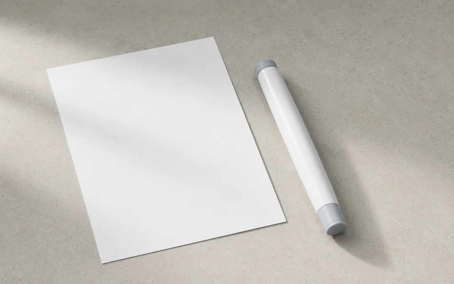 A plain unbranded medical injector pen resting on a calm neutral surface beside a blank document